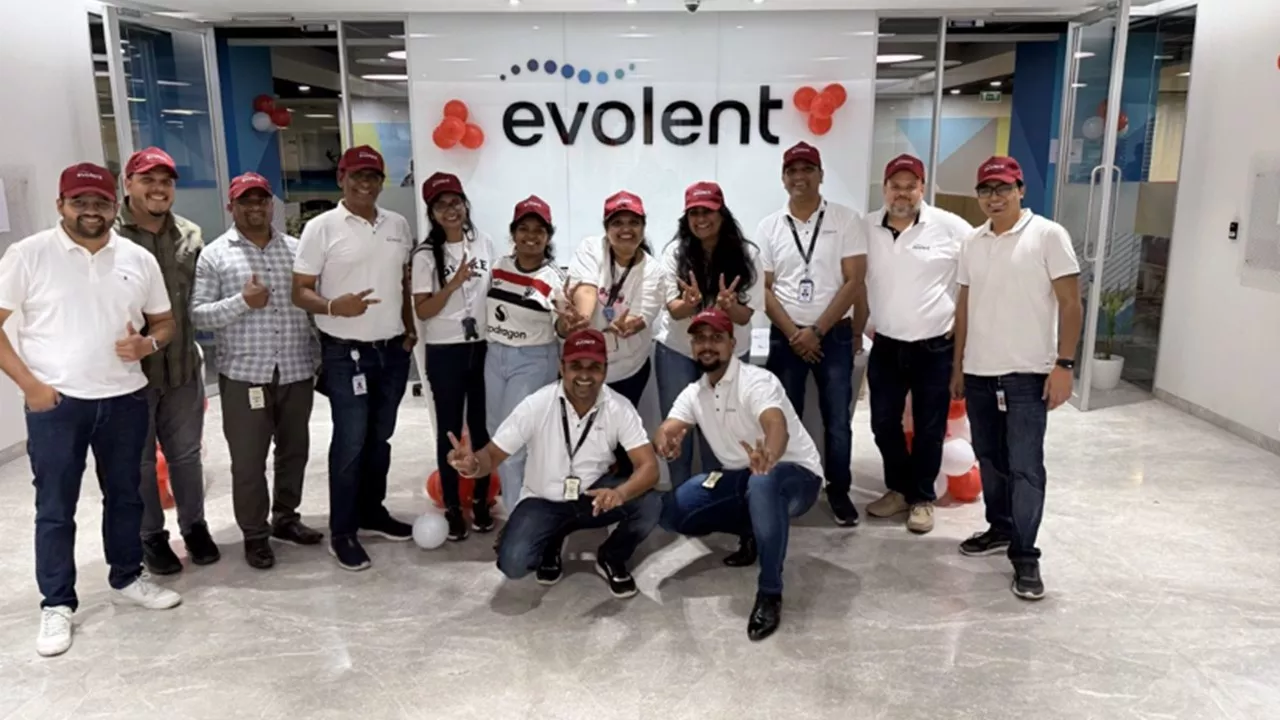 11 smiling employees posing in front of Evolent logo in the company's Pune, India, office, showcasing Evolent's global footprint